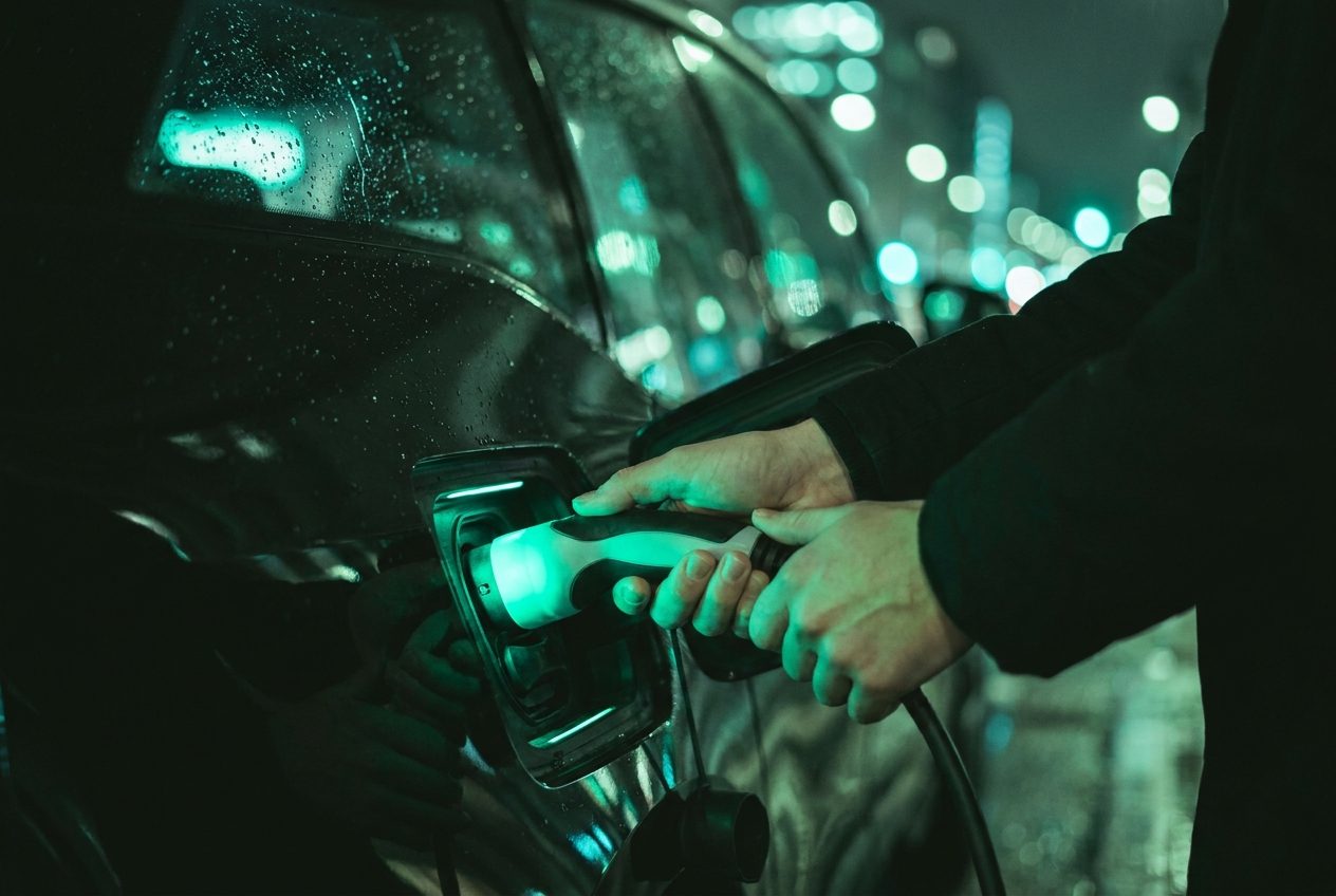 Plugging a glowing charging cable into an electric car at night
